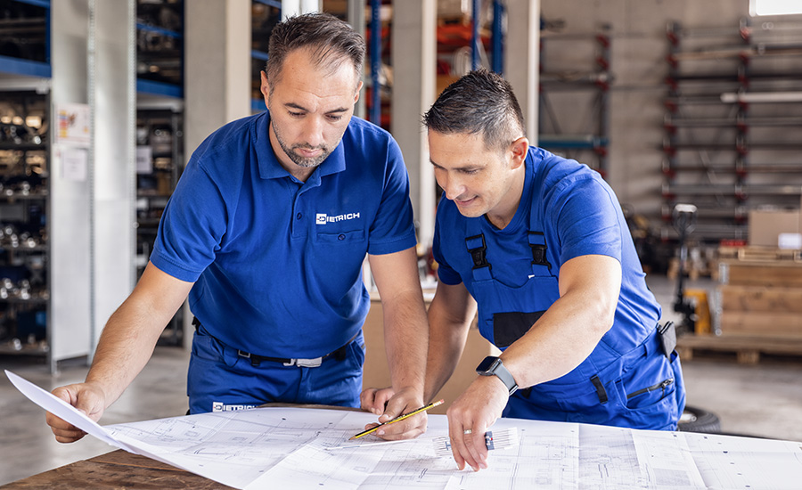 Zwei Mitglieder des Bereiches der Gebäudetechnik der Dietrich GmbH betrachten gemeinsam Baupläne.